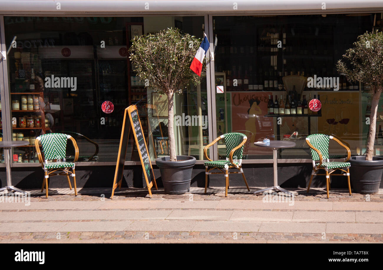French cafe terrace flies the tri-colors in front of restaurant and shop.  Outside image with chairs, tables, billbords and olive trees. Copenhagen,  De Stock Photo - Alamy