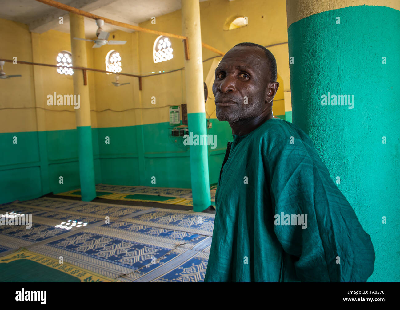 African man in green clothes inside a mosque, Denguélé, Korondougou, Ivory Coast Stock Photo