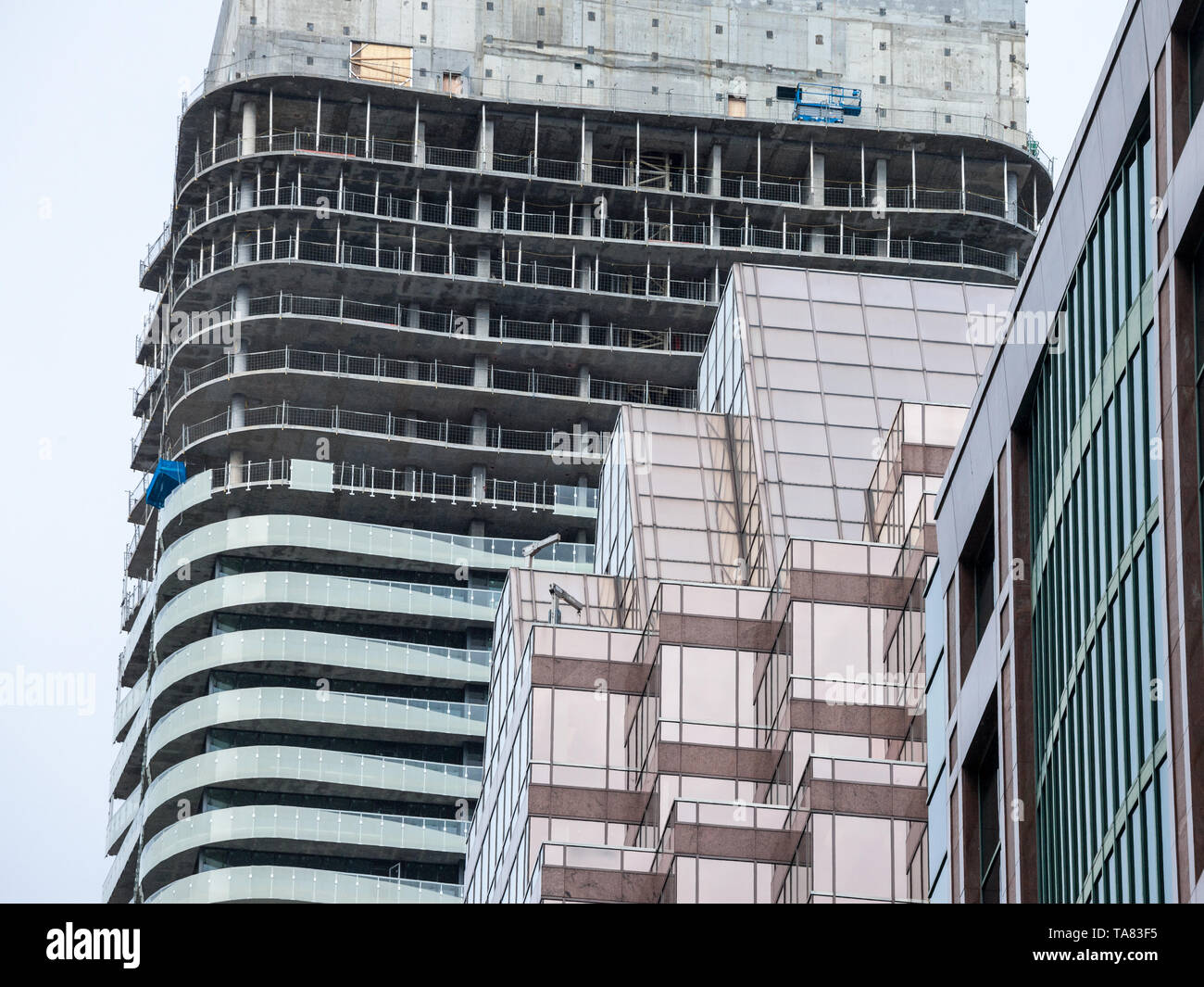 Cranes and building device on a construction site of a skyscraper in downtown Toronto, surrounded by other high rise towers and condos as well as olde Stock Photo