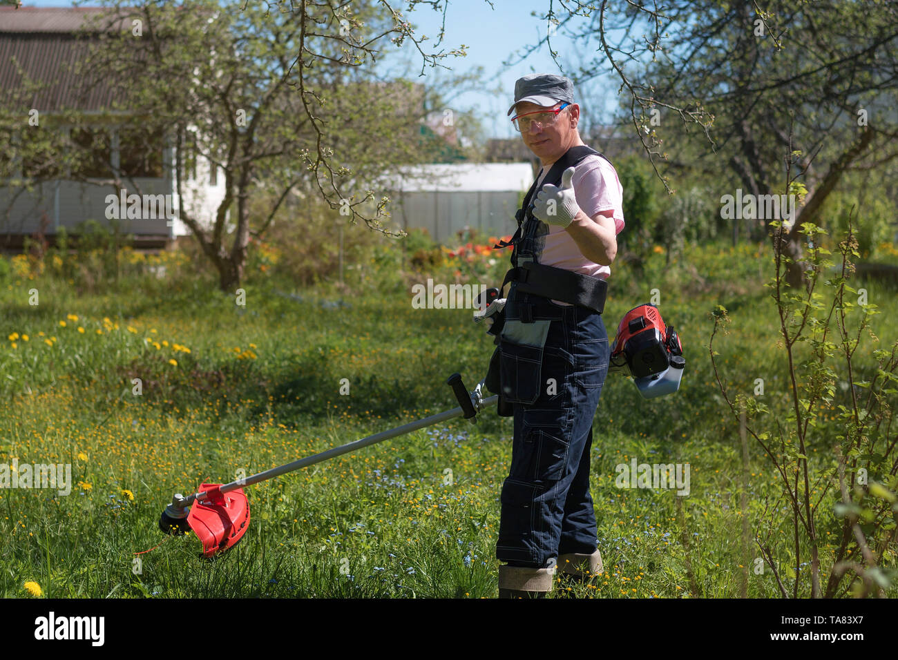 A man mows the grass on the lawn mowers. Overalls and tools Stock Photo