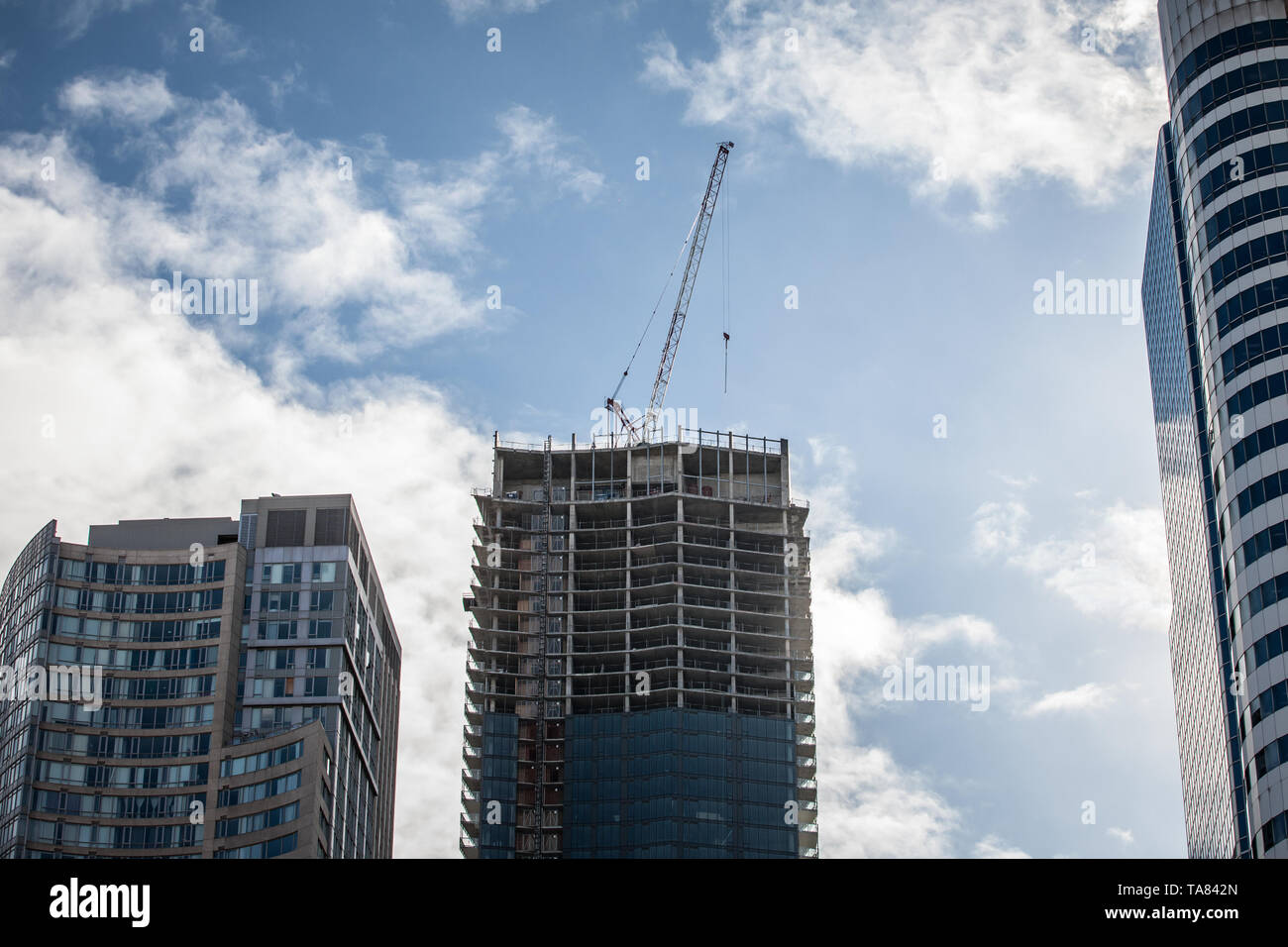 Cranes and building devices on a construction site of a skyscraper in downtown Toronto, surrounded by other high rise towers and condos as well as old Stock Photo