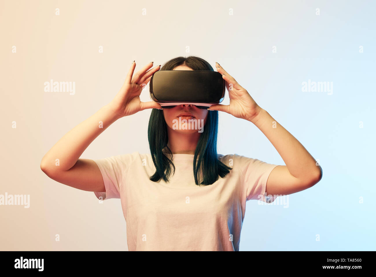 brunette young woman touching virtual reality headset on beige and blue ...