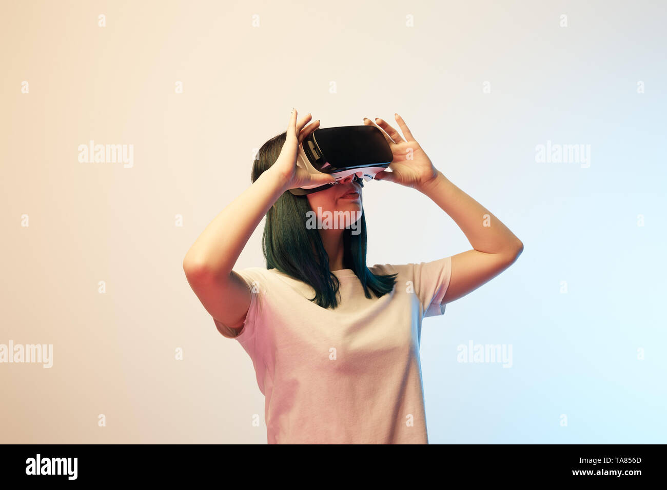 attractive young woman touching virtual reality headset on beige and ...