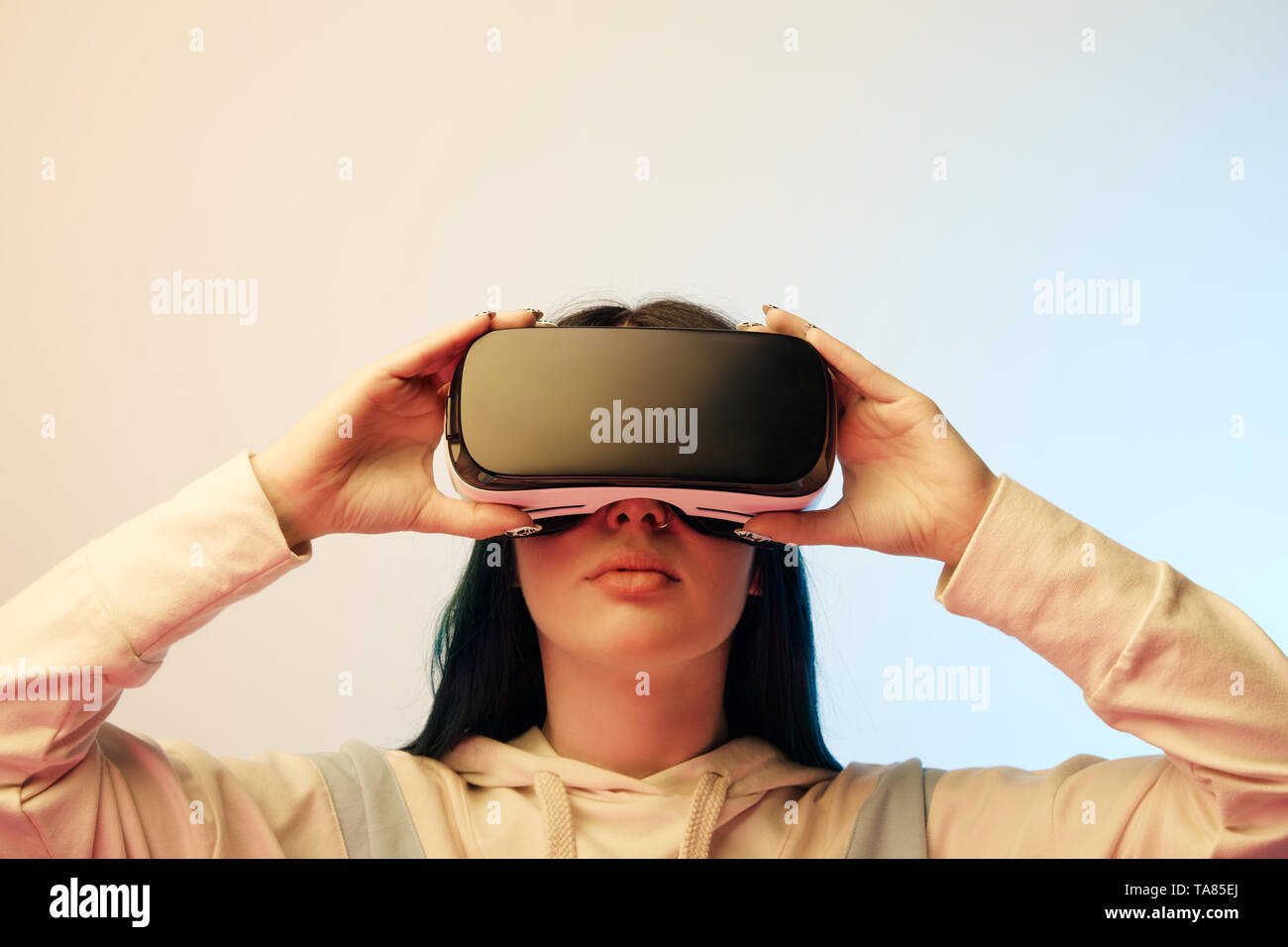beautiful young woman touching virtual reality headset on beige and ...