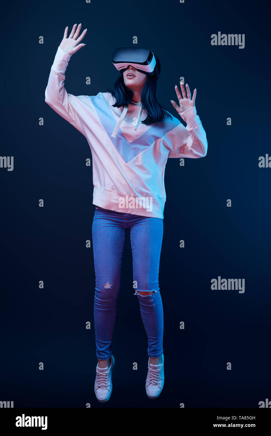 brunette young woman gesturing while wearing virtual reality headset on ...