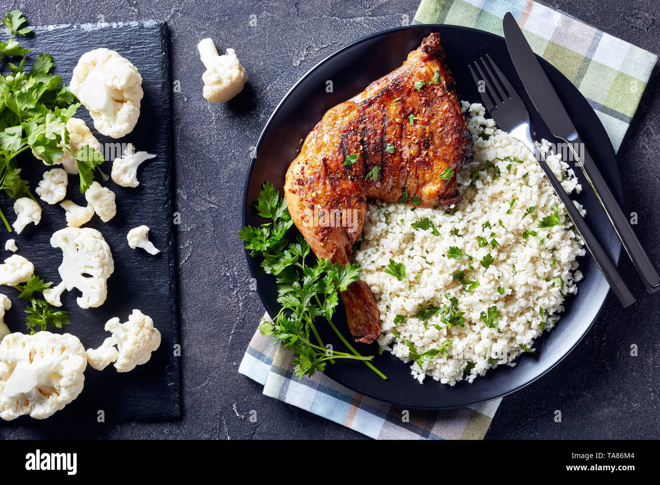 grilled chicken leg quarter served with Cauliflower rice or couscous in a black bowl on a