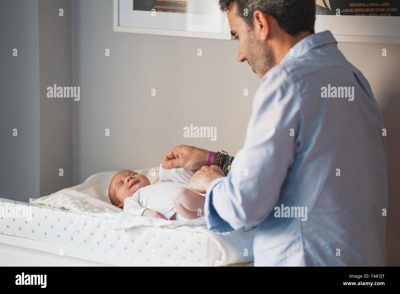 New father changing the diaper to his cute newborn. Baby expresses calm and peace. Social and Gender equality. Family, new life, childhood, fatherhood Stock Photo