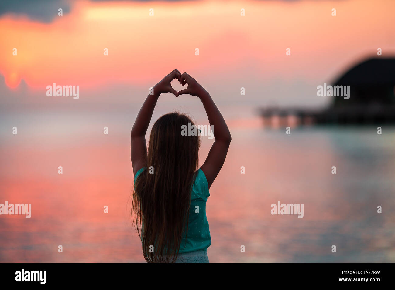 Silhouette of heart made by kids hand at sunset Stock Photo