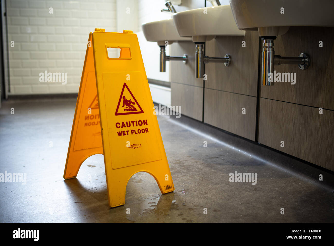 Caution wet floor safety stand up yellow warning sign in a toilet Stock