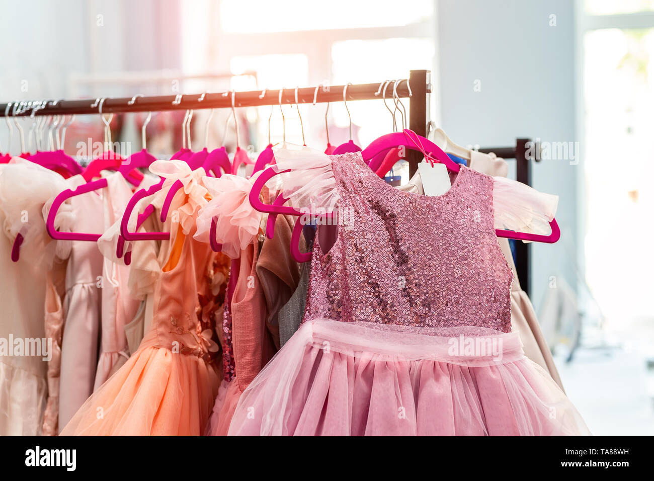 Rack with many beautiful holiday dresses for girls on hangers at children  fashion showroom indoor. Kid girl dress hire studio for celebration  birthday Stock Photo - Alamy