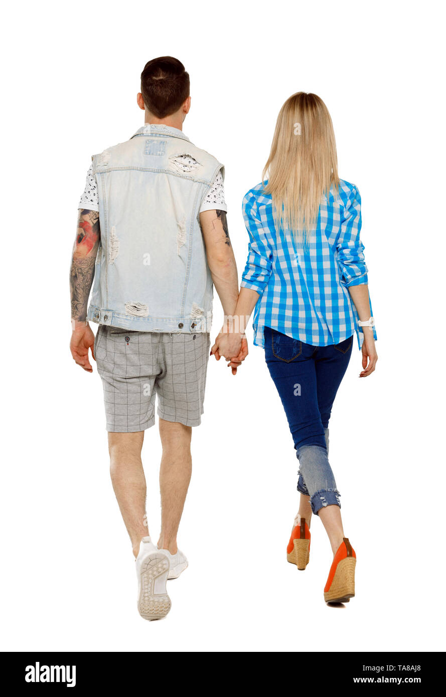 Back view of going couple. walking friendly girl and guy holding hands