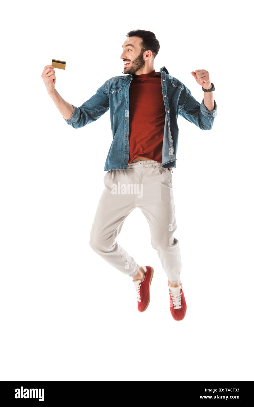 happy man jumping and showing yes gesture while holding credit card isolated on white Stock Photo