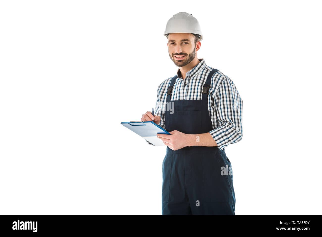 smiling construction worker writing on clipboard and looking at camera isolated on white Stock Photo