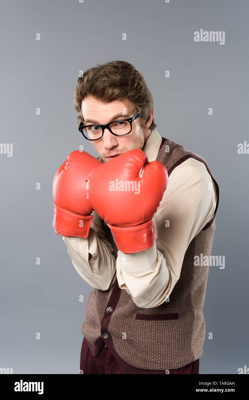 serious man in glasses and boxing posing on grey background Stock Photo