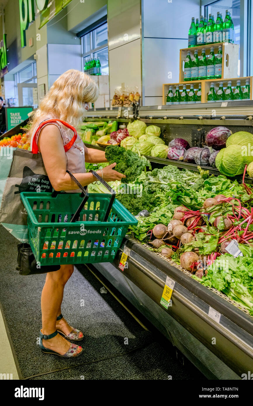woman buying kale in supermarket Stock Photo