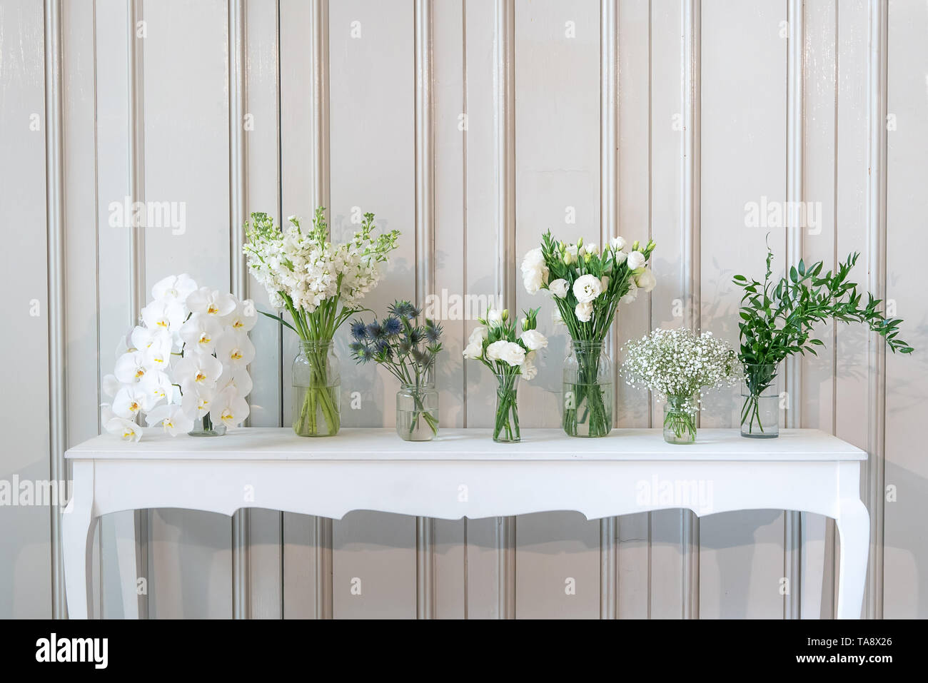 simply composition of different white flower in vase on white vintage table Stock Photo