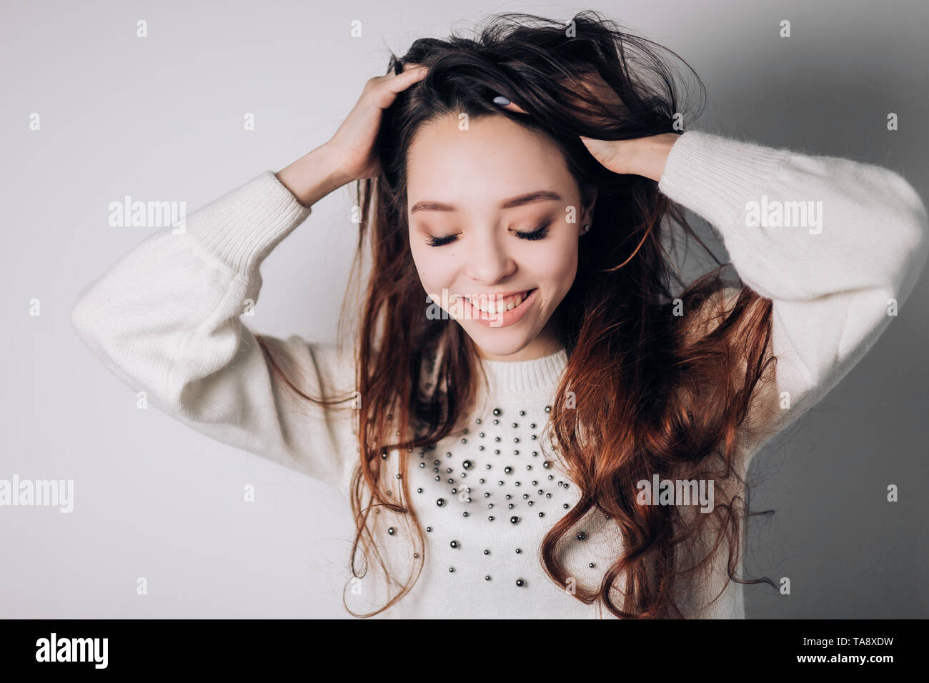 A Beautiful Smiling Woman Lifts Her Thick Hair Looks Down On A