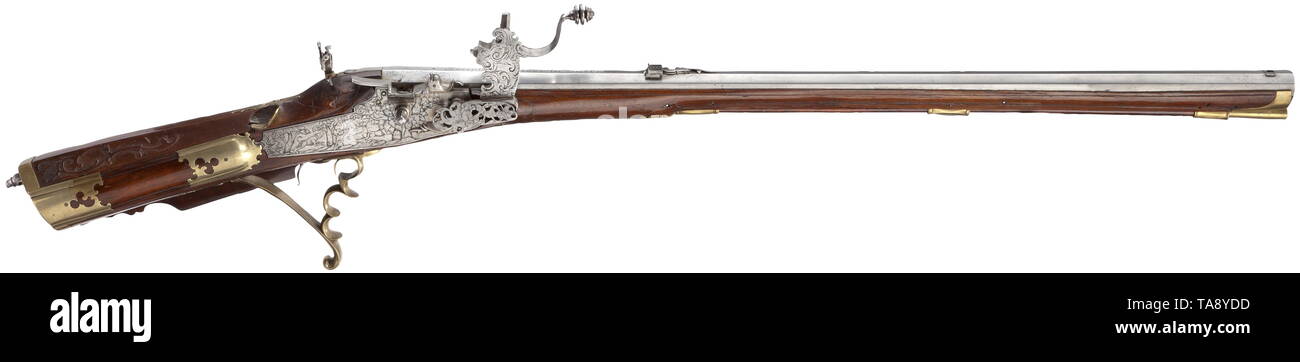A wheellock rifle, Joseph Gruber, Tulln, circa 1730 Rifled bore in 14 mm calibre, on barrel top signature and adjustable cut rear sight. Wheellock with engraved and cut hunting scenes. Set trigger (shortened). Carved full stock with brass furniture repaired in places. Aperture sight behind tang. Wooden ramrod with brass tip. Length 114 cm. Comes with modern wheellock key. historic, historical, shoulder arm, weapons, arms, weapon, arm, military, militaria, firearm, fire arm, gun, fire arms, firearms, guns, weapon, arms, weapons, arms, object, obje, Additional-Rights-Clearance-Info-Not-Available Stock Photo