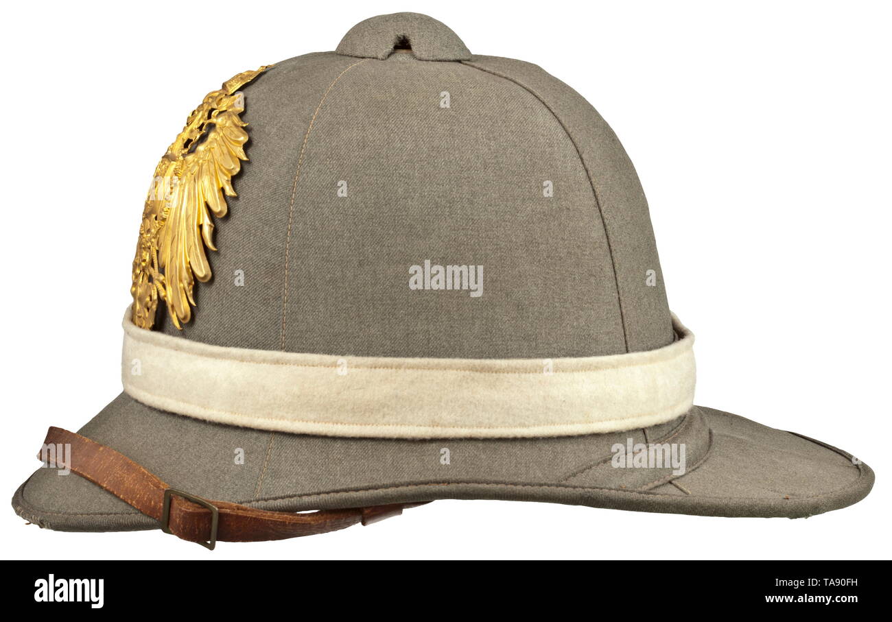 A tropical helmet M 1900 of the East Asiatic Expeditionary Corps Depot piece. Cork body with field-grey textile covering and edging (blemishes), unscrewable ventilation cap and folding neck guard. Green liner, brown leather sweatband with size stamping '54 1/2', embossed maker's crest and lettering 'Ludwig Bortfeldt Bremen', brown chinstrap with brass slides. The neck guard underside stamped 'B.A.O. 1903' and quadruple stamped '10 IR - I.B. - 3.K. - 1905'. Pinned on golden imperial eagle, trim band in white arm of service colour with pinned lacqu, Additional-Rights-Clearance-Info-Not-Available Stock Photo