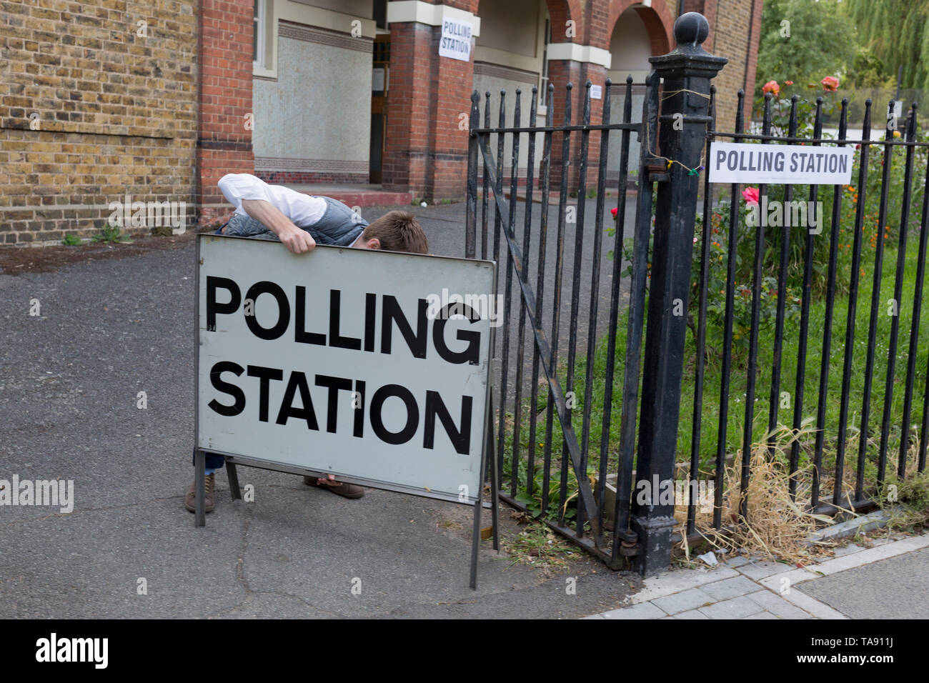 Before voting for the European Elections commences at 7am, an official carries a Polling Station sign to the entrance of St. Saviour's church hall in Herne Hill, on 23rd May 2019, in Lambeth, south London, England UK. Stock Photo