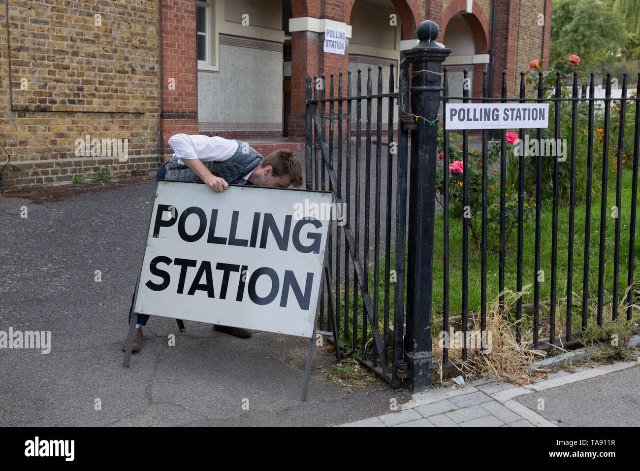 Before voting for the European Elections commences at 7am, an official carries a Polling Station sign to the entrance of St. Saviour's church hall in Herne Hill, on 23rd May 2019, in Lambeth, south London, England UK. Stock Photo