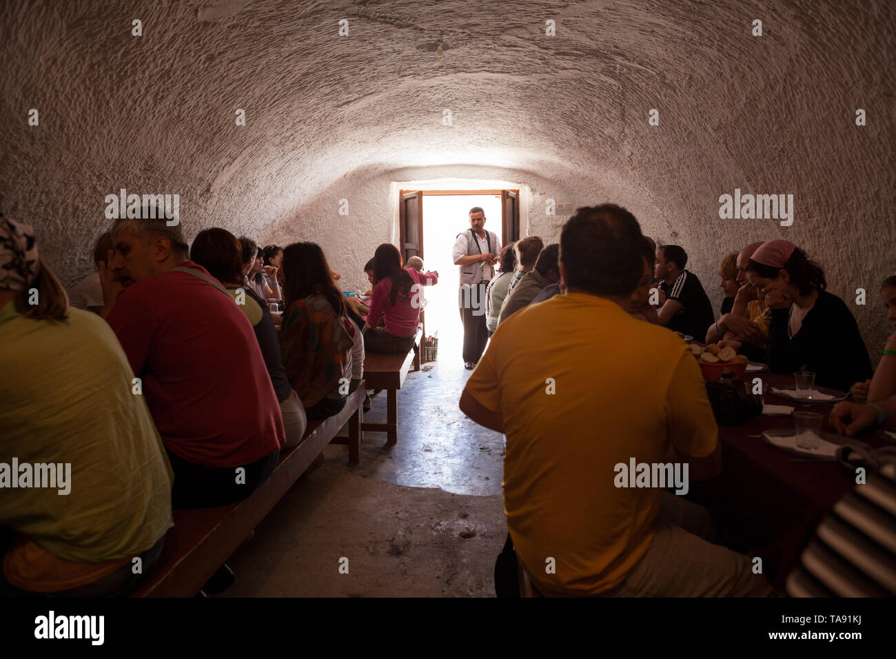 MATMATA, TUNISIA-CIRCA MAY, 2012: Tourists have lunch at bus tour in Sahara desert. Traditional underground troglodyte style dining room is carved in  Stock Photo
