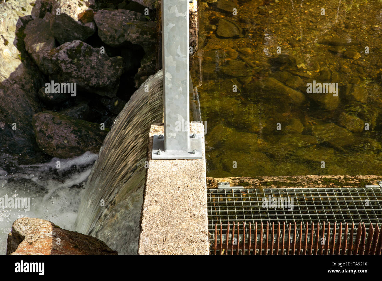 Spillway over a small dam close up. Water level difference. Regulation of the water level in the lake. Stock Photo