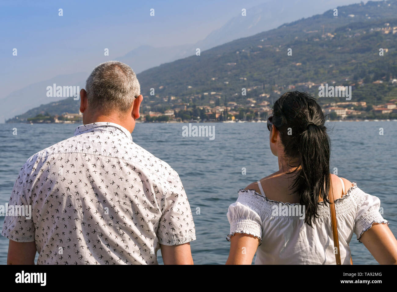GARDA, LAKE GARDA, ITALY - SEPTEMBER 2018: Two people standing on a  passenger ferry on a journey across Lake Garda looking out at the scenery. Stock Photo