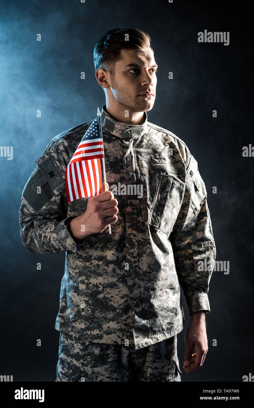 confident soldier in military uniform holding american flag on black ...