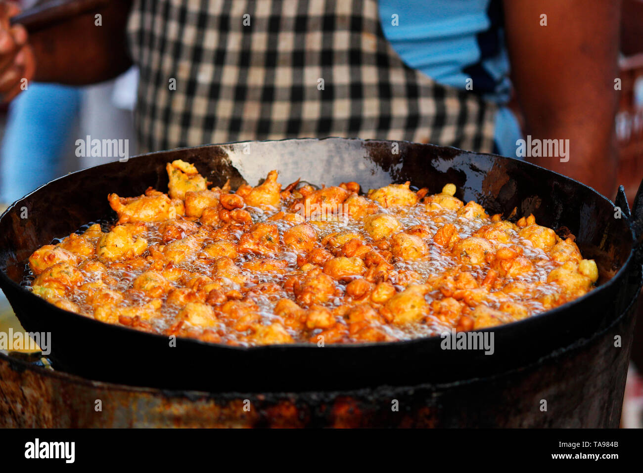 Man frying spicy snack or entree dish similar to a fritter, bhajji on street. Stock Photo