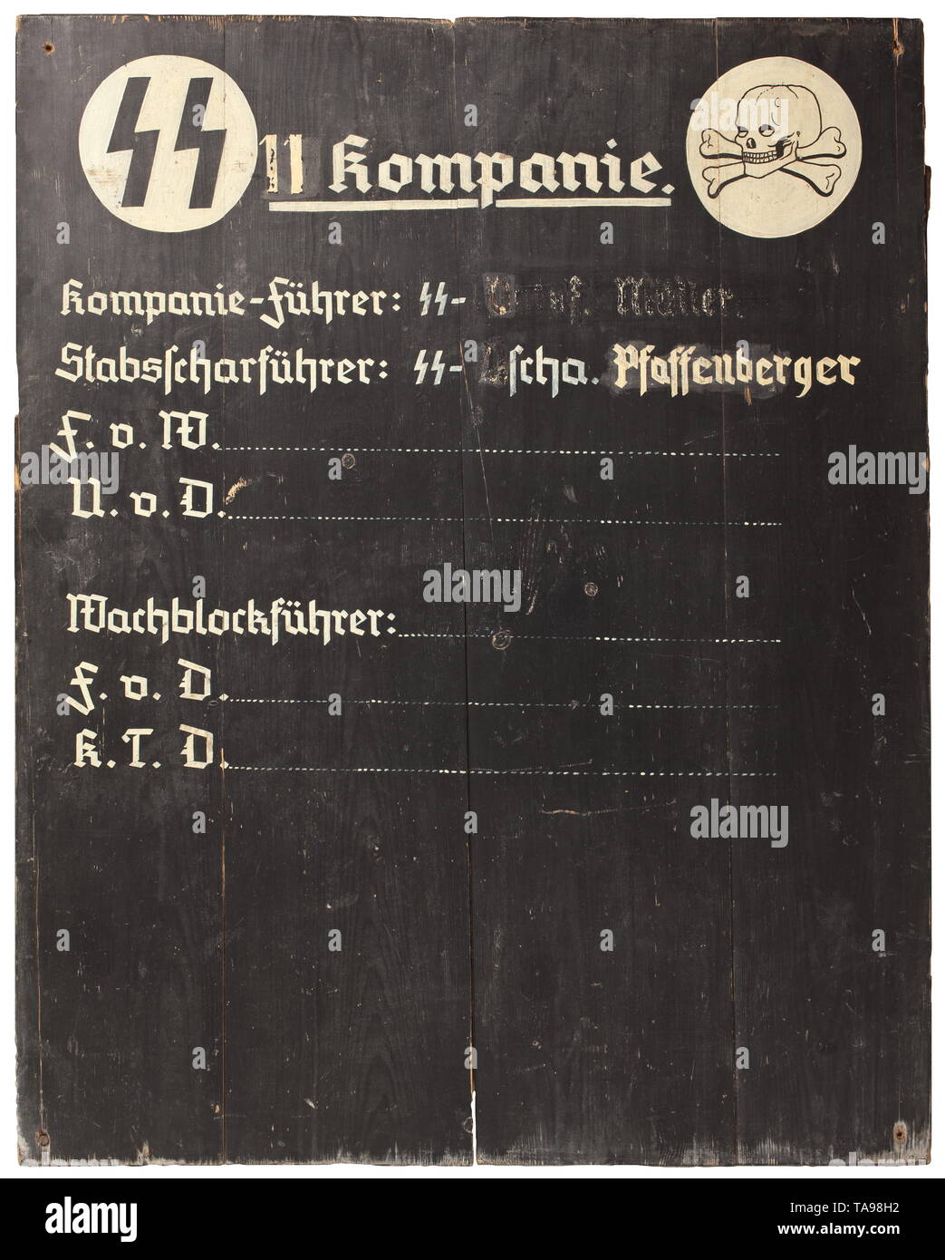 An SS duty board of an 11th company Timbered from four wooden planks, front side painted black, with SS runes and skull on white disks, in between '11. Kompanie', beneath it 'Kompanie-Führer: SS-Ostuf Müller - Stabsscharführer: SS-U.Scha. Pfaffenberger' (partly smeared letters), alternating duties 'F.v.W. - U.v.D. - Wachblockführer - F.v.D. - K.T.D.' with blank lines. Reverse side painted field-grey and with chalk tactical drawings. In the corners very worn mounting holes. Dimensions 120.5 x 96.85 cm. Extremely rare. The simple but solid workmanship implies the mobile use o, Editorial-Use-Only Stock Photo