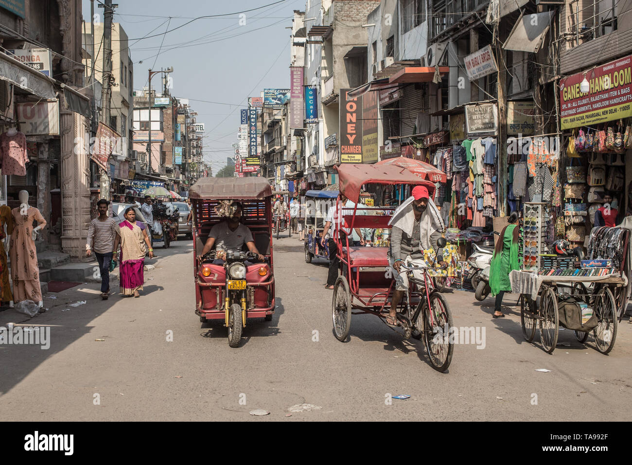 An electrical rickshaw and bicycle rickshaw on a street in downtown New Delhi, India. Stock Photo