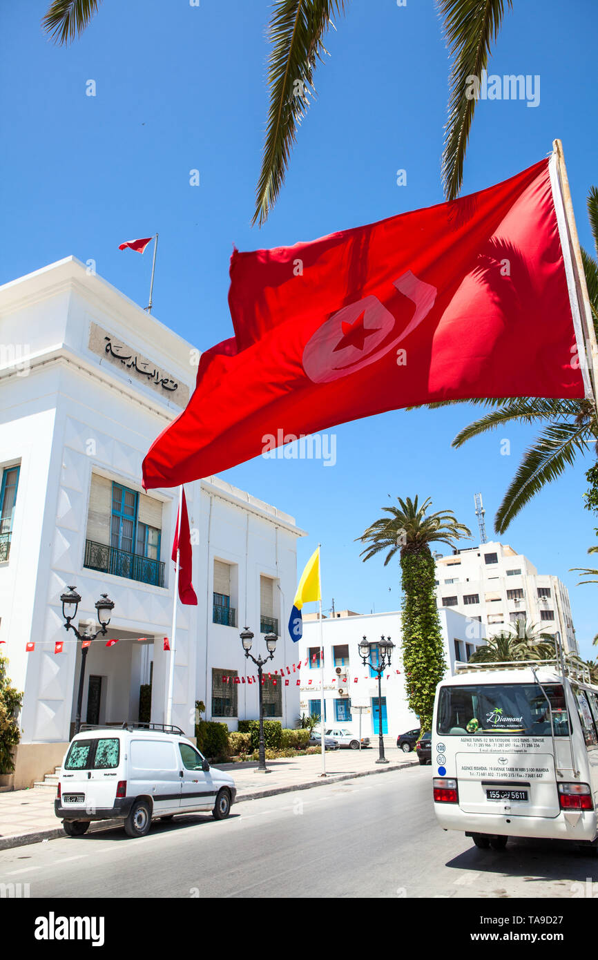 SOUSSE, TUNISIA, AFRICA-CIRCA MAY, 2012: Tunisian national flag waves against administrative building in Sousse city. All government buildings must ha Stock Photo