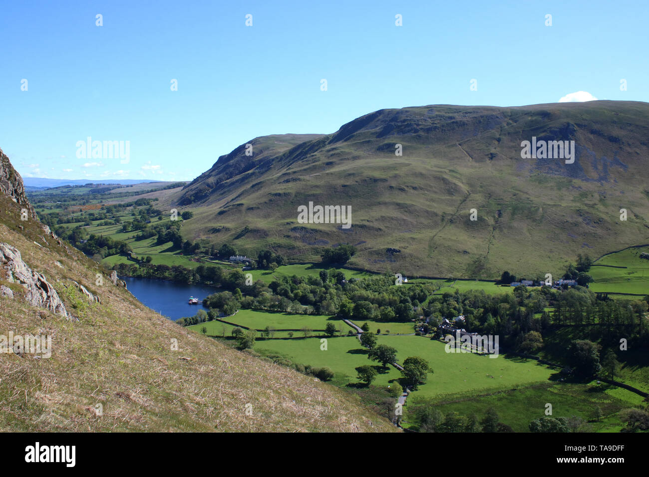 View northeast from slopes of Hallin Fell across Howtown, with steamer at pier, towards Bonscale Pike and Arthur's Pike in English Lake District. Stock Photo