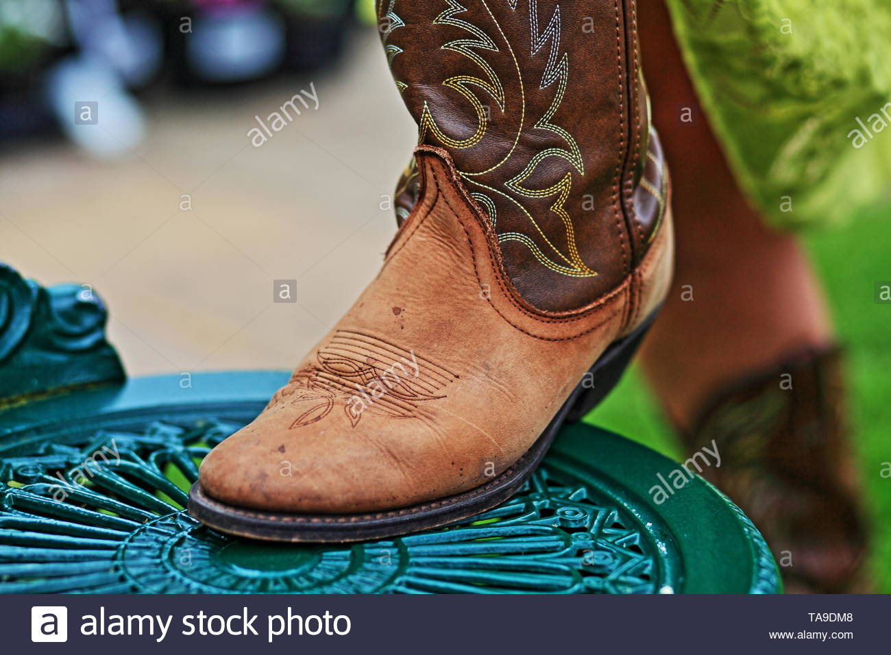 Image Of A Woman Foot In A Cowboy Boot On A Wrought Iron Chair