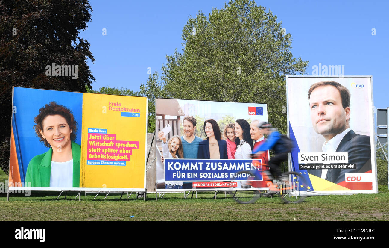 30 April 2019, Hessen, Frankfurt/Main: In the east of Frankfurt, a cyclist drives past election posters of the FDP (l-r), SPD and CDU for the European elections. The direct election to the European Parliament will take place in Germany on 26 May 2019. 4.7 million Hesse are called to vote. Photo: Arne Dedert/dpa Stock Photo