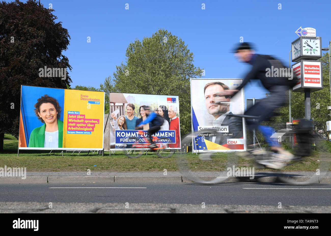 30 April 2019, Hessen, Frankfurt/Main: Cyclists in the east of Frankfurt pass election posters of the FDP (l-r), SPD and CDU for the European elections. The direct election to the European Parliament will take place in Germany on 26 May 2019. 4.7 million Hesse are called to vote. Photo: Arne Dedert/dpa Stock Photo