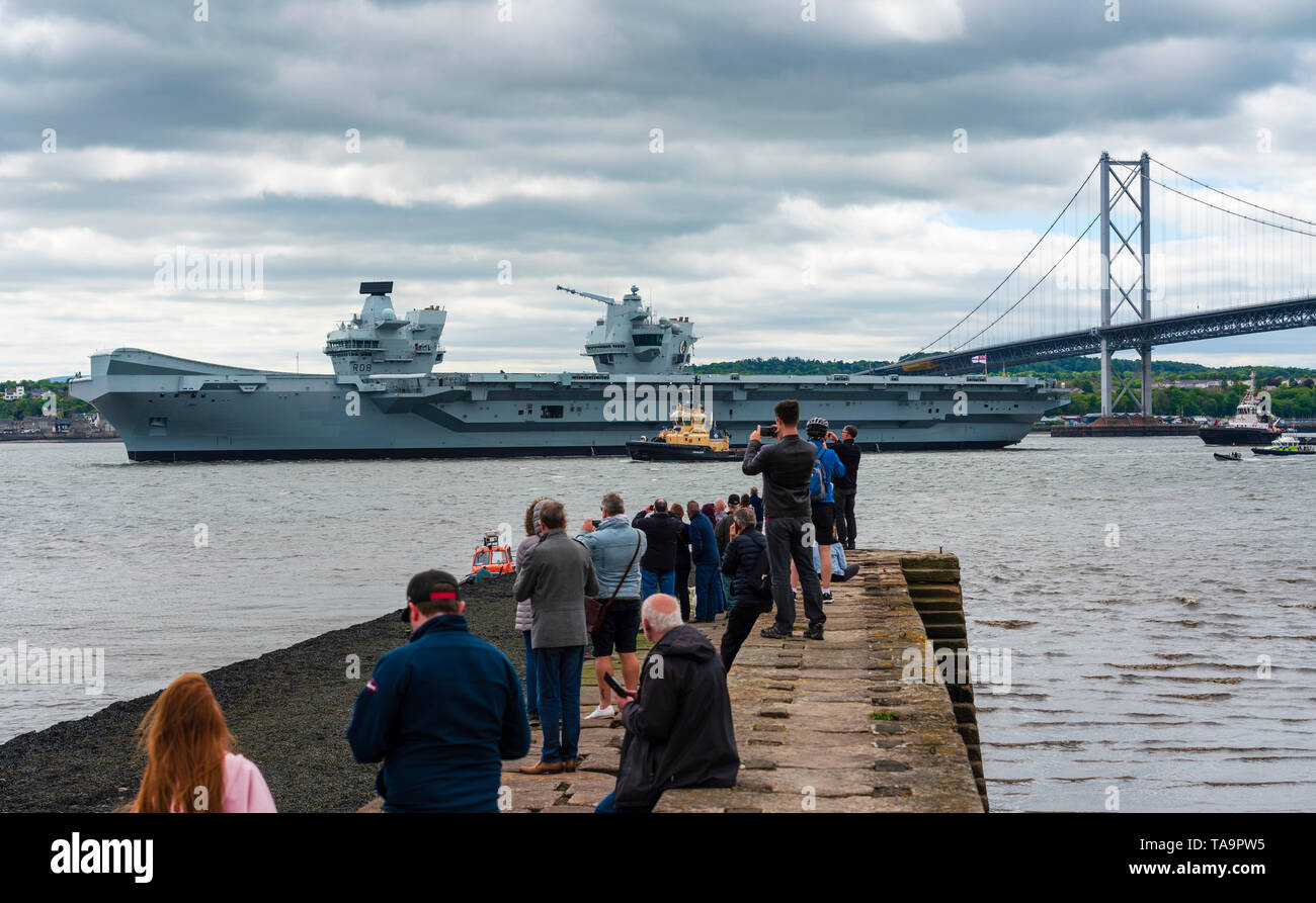 North Queensferry, Scotland, UK. 23rd May, 2019. Aircraft carrier HMS Queen Elizabeth sails from Rosyth in the River Forth after a visit to her home port for a refit. She returns to sea for Westlant 19 deployment and designed to focus on the operations of her F-35 fighter aircraft. Pictured; People gathered at North Queensferry pier to watch the carrier depart the River Forth. Credit: Iain Masterton/Alamy Live News Stock Photo