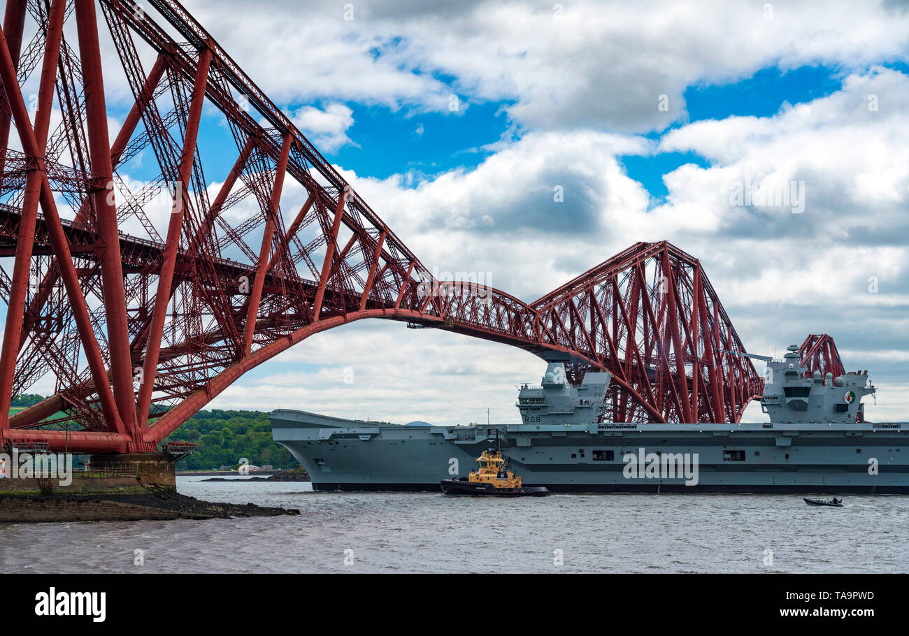 North Queensferry, Scotland, UK. 23rd May, 2019. Aircraft carrier HMS Queen Elizabeth sails from Rosyth in the River Forth after a visit to her home port for a refit. She returns to sea for Westlant 19 deployment and designed to focus on the operations of her F-35 fighter aircraft. Pictured; The Carrier passes below the Forth Bridge at low tide. Credit: Iain Masterton/Alamy Live News Stock Photo