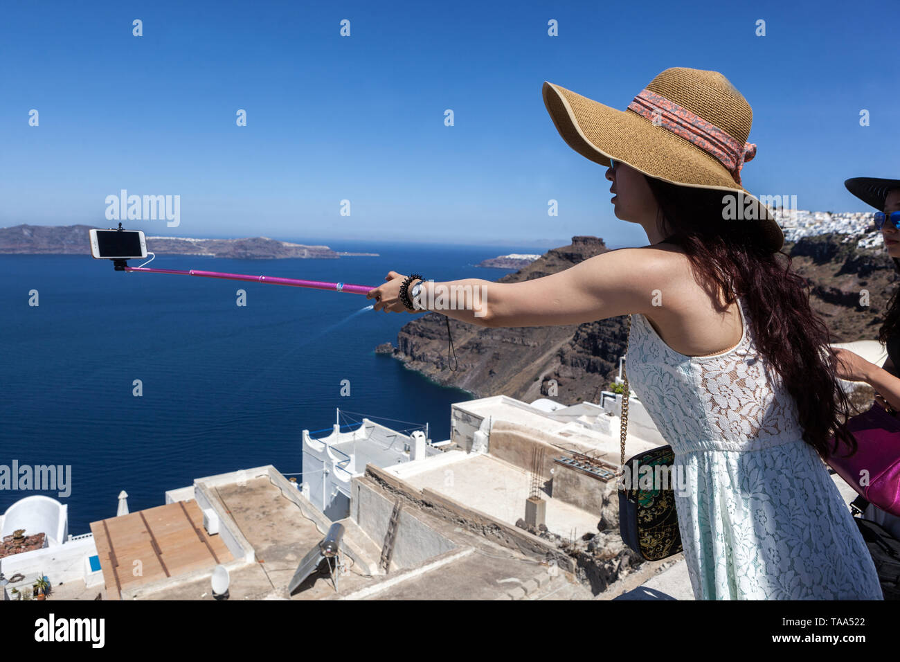 Greece Santorini People Tourists, Young Asian woman making photo, selfie above caldera Europe Stock Photo