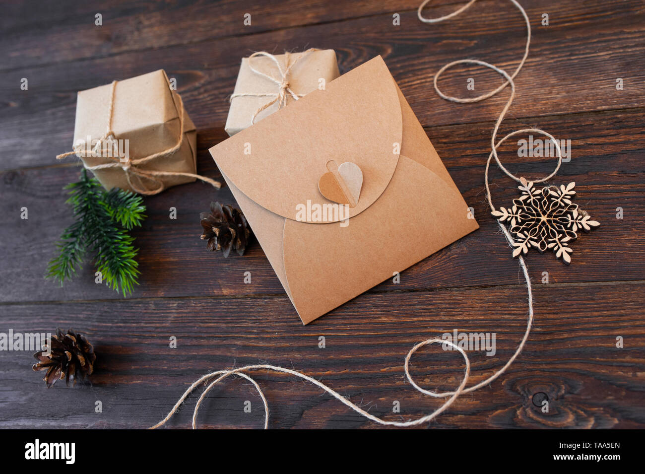 mockup Christmas kraft gift boxes with xmas wooden toys on wooden background. Top view for greeting card with place for text Stock Photo