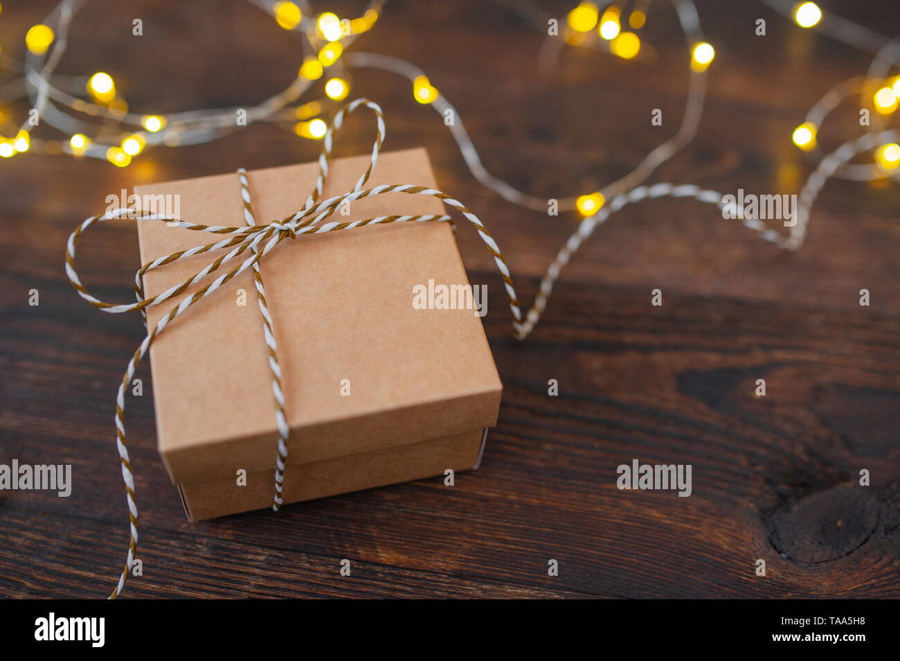 mockup Christmas kraft gift box with xmas garland on wooden background. Top view for greeting card with place for text Stock Photo
