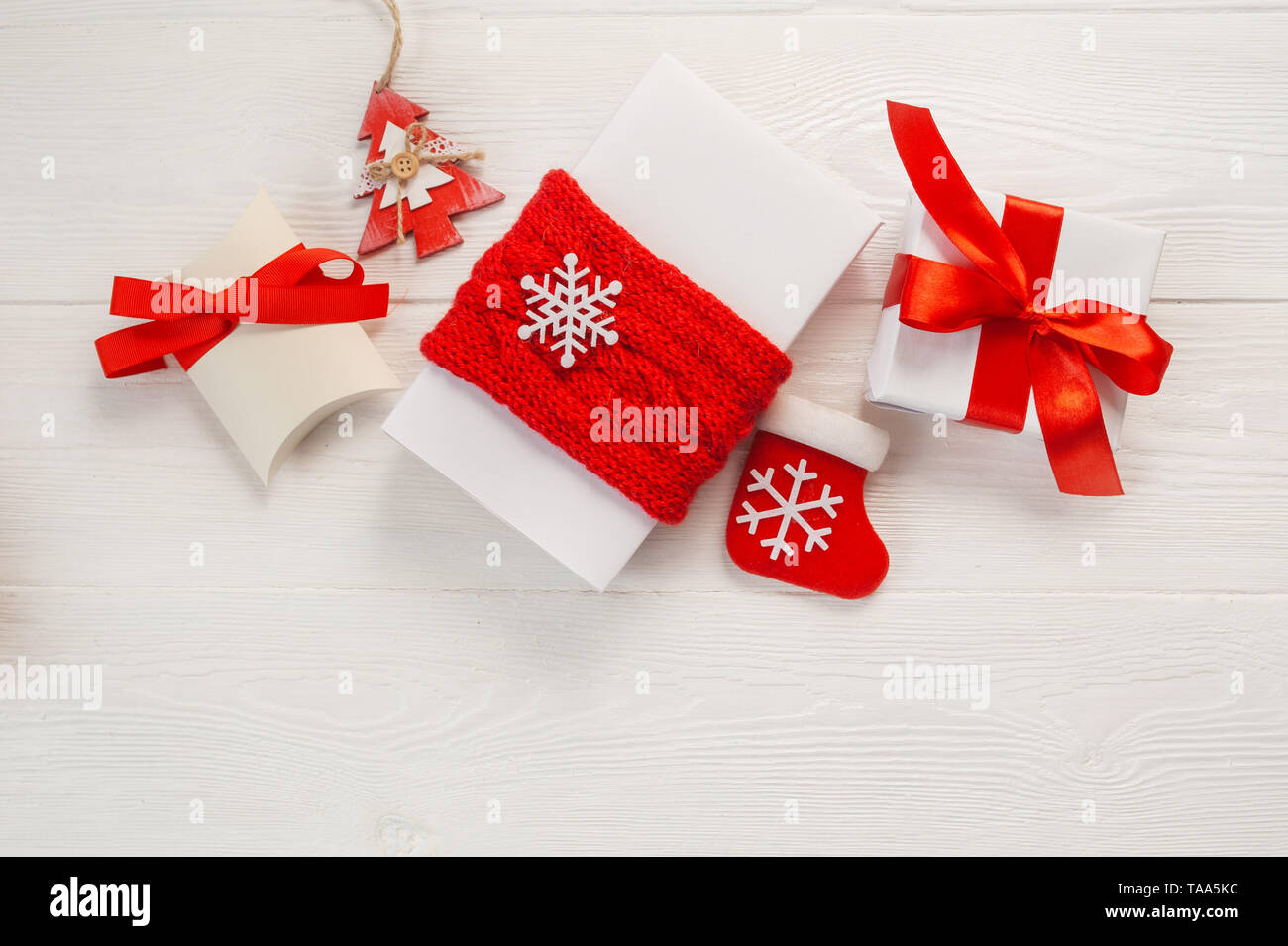 Christmas greetings card. White and kraft gift boxes with red ribbon and bump on a wooden background with place for your text Stock Photo
