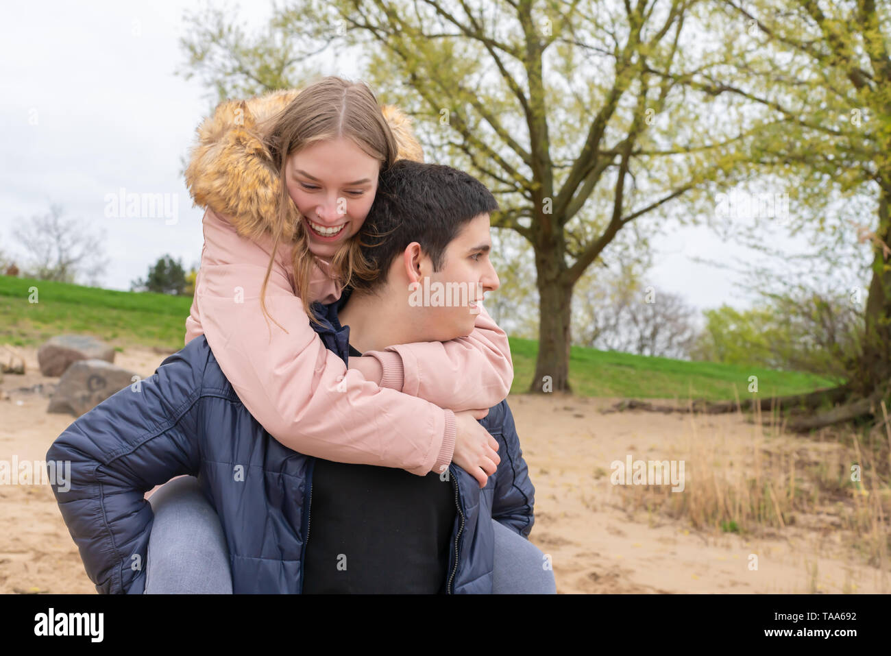 A young couple on the beach wearing them piggyback Stock Photo - Alamy