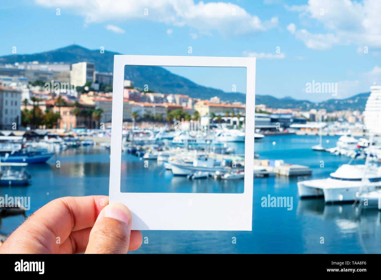 closeup of a young caucasian man with a white frame in his hand, at the Port of Ajaccio, simulating an instant photograph Stock Photo