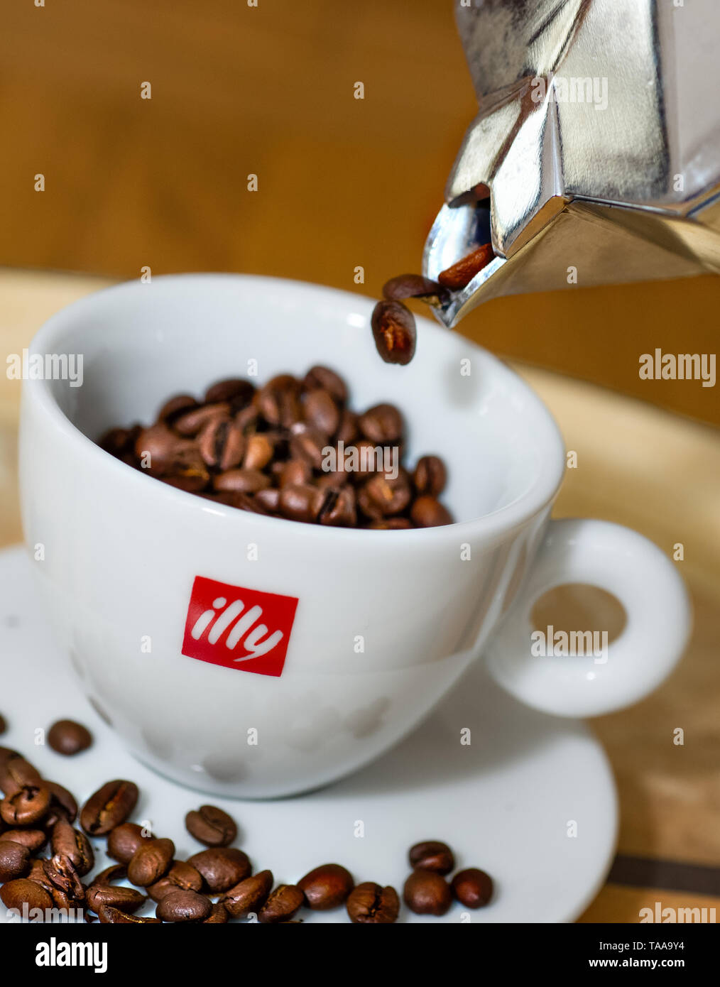 Coffee beans being poured from Bialetti coffee maker into Illy cups