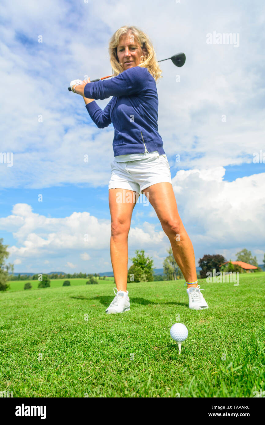 Blonde woman hitting a golf ball from tee with driver Stock Photo - Alamy