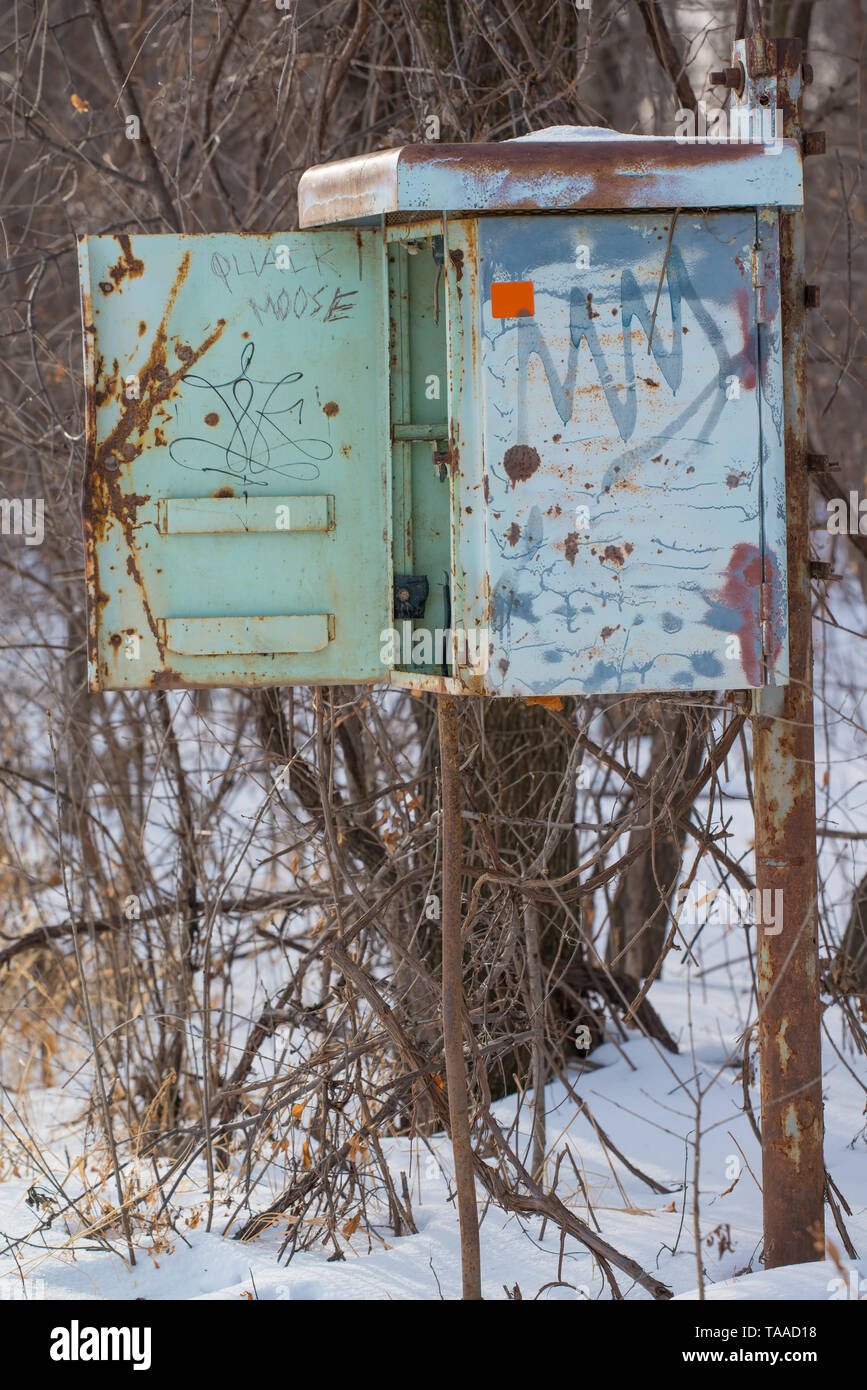 A rusty vintage old phone box (I think) on a pole that no longer had a phone in it - next to remote area railroad tracks - cold snowy wintery day Stock Photo