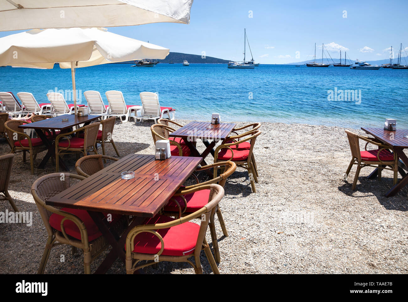 Wooden chairs with tables on the beach at seaside restaurant in Bodrum