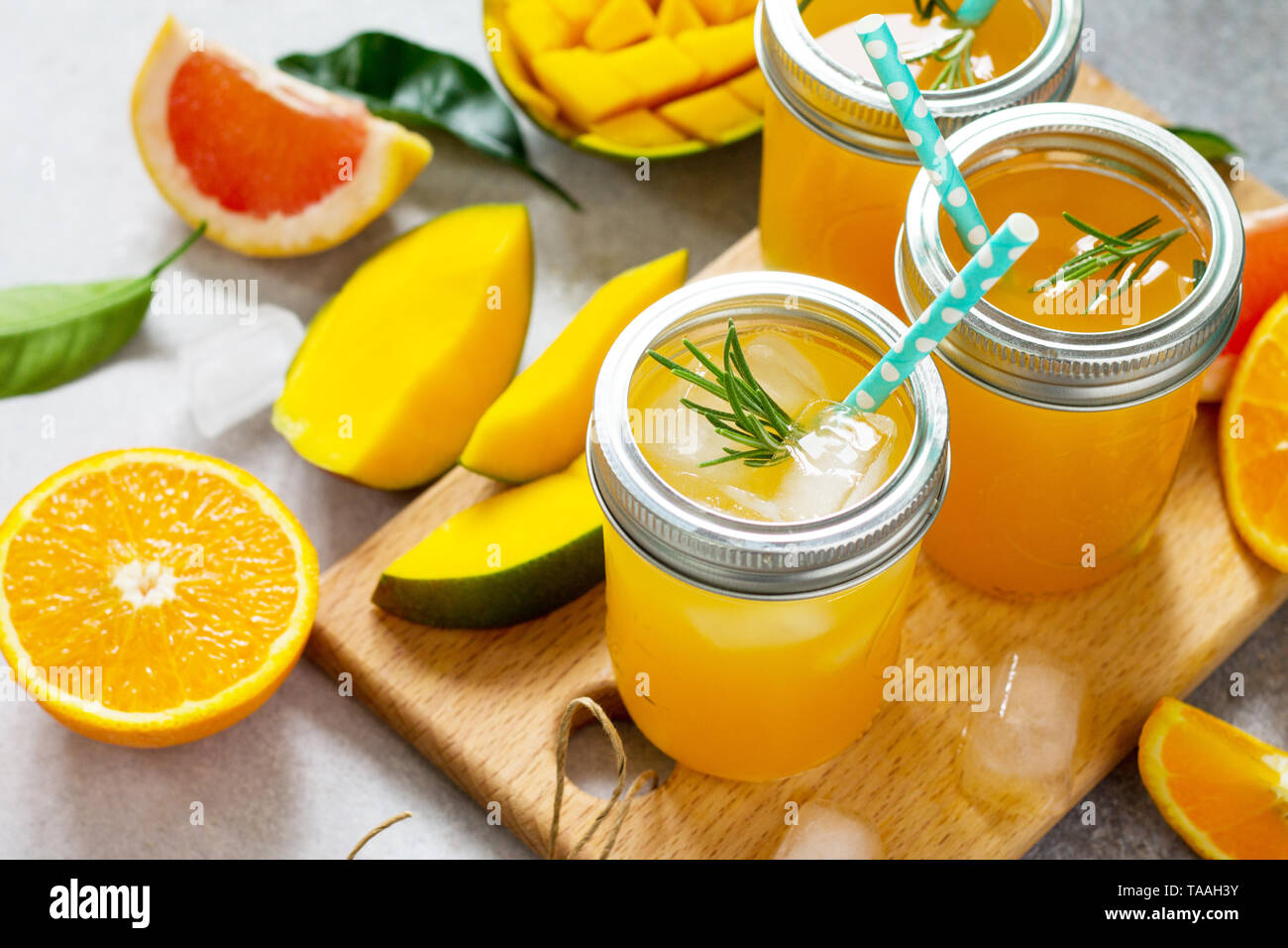 Refreshing summer cocktails made of citrus and mango, cold drink with ice on a stone or slate background. Concept fresh vitamins. Rustic style. Stock Photo